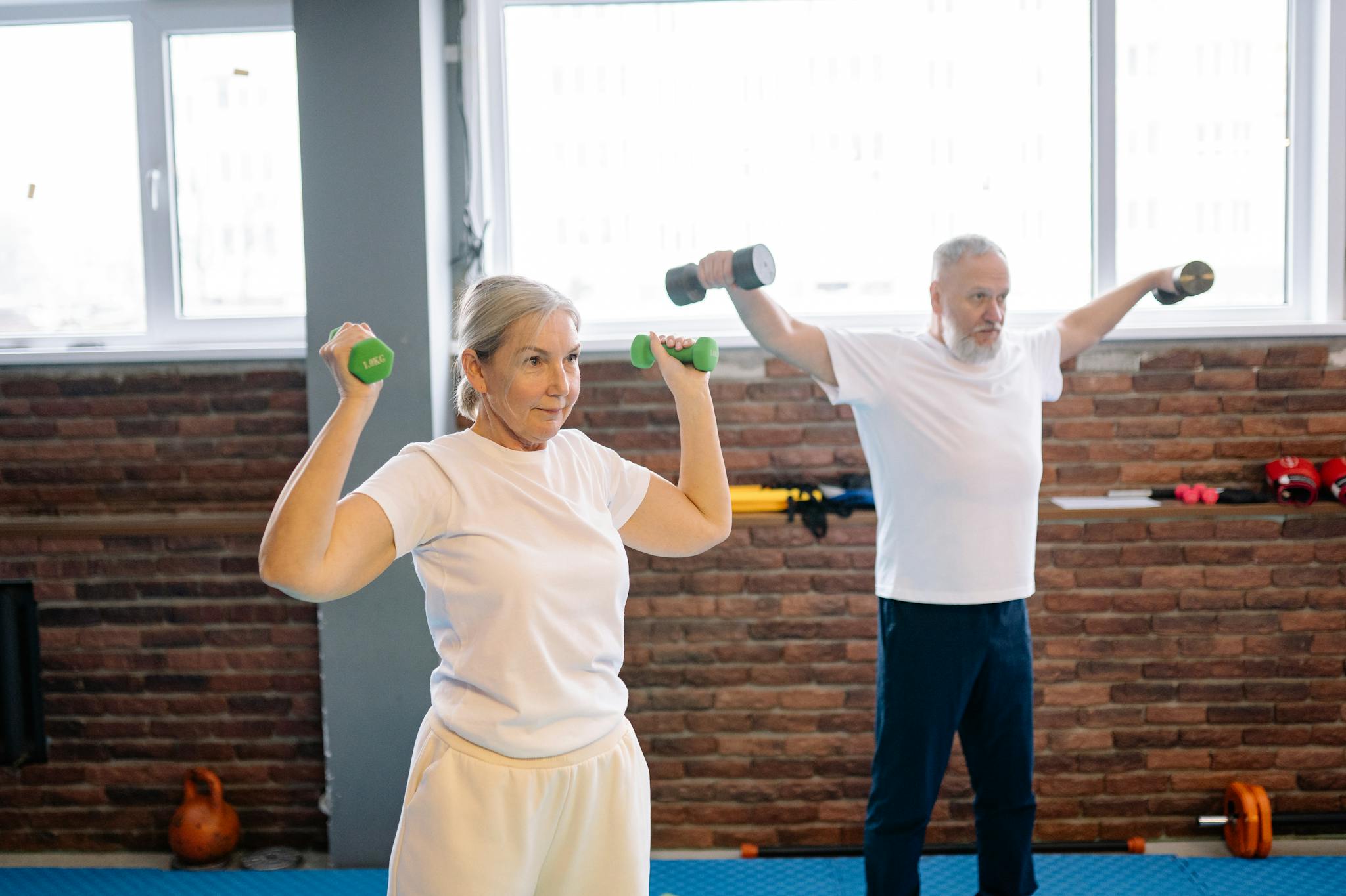 Elderly man and woman workout with dumbbells promoting healthy lifestyle and fitness.