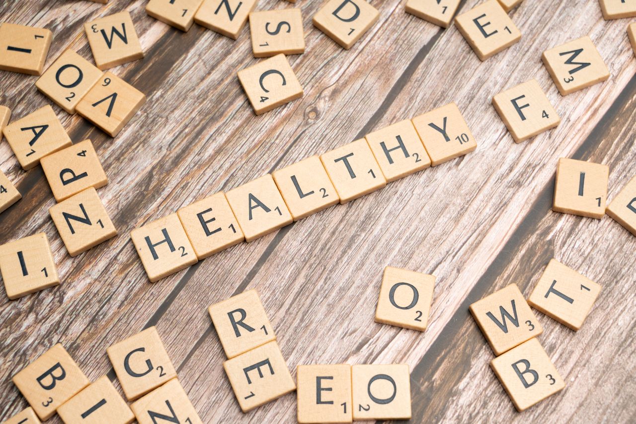 heros-img Wooden letter tiles arranged on a wooden surface spelling out 'healthy', symbolizing wellness.